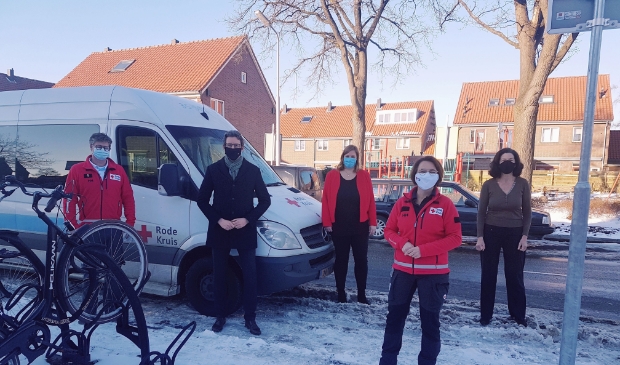 Burgemeester Tjapko Poppens met medewerkers van het Rode Kruis bij een van de bussen van de organisatie.
