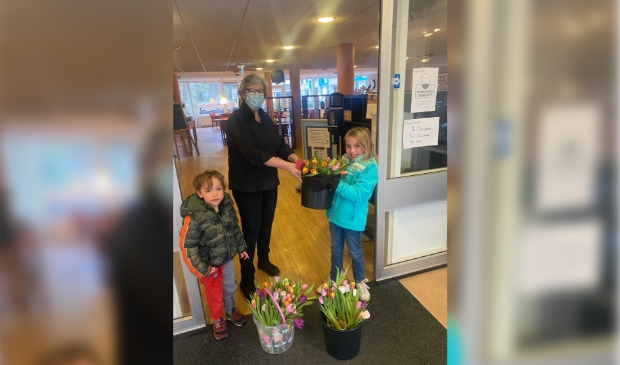 Sterre overhandigt de bloemen aan een medewerkster van Sparrenheide. Links op de foto haar broertje Jan.