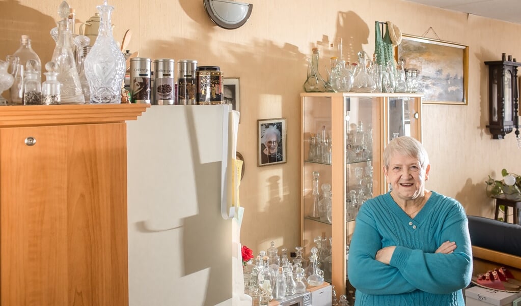 Bets ten Broek in haar woonkamer tussen de flesjes van witglas.