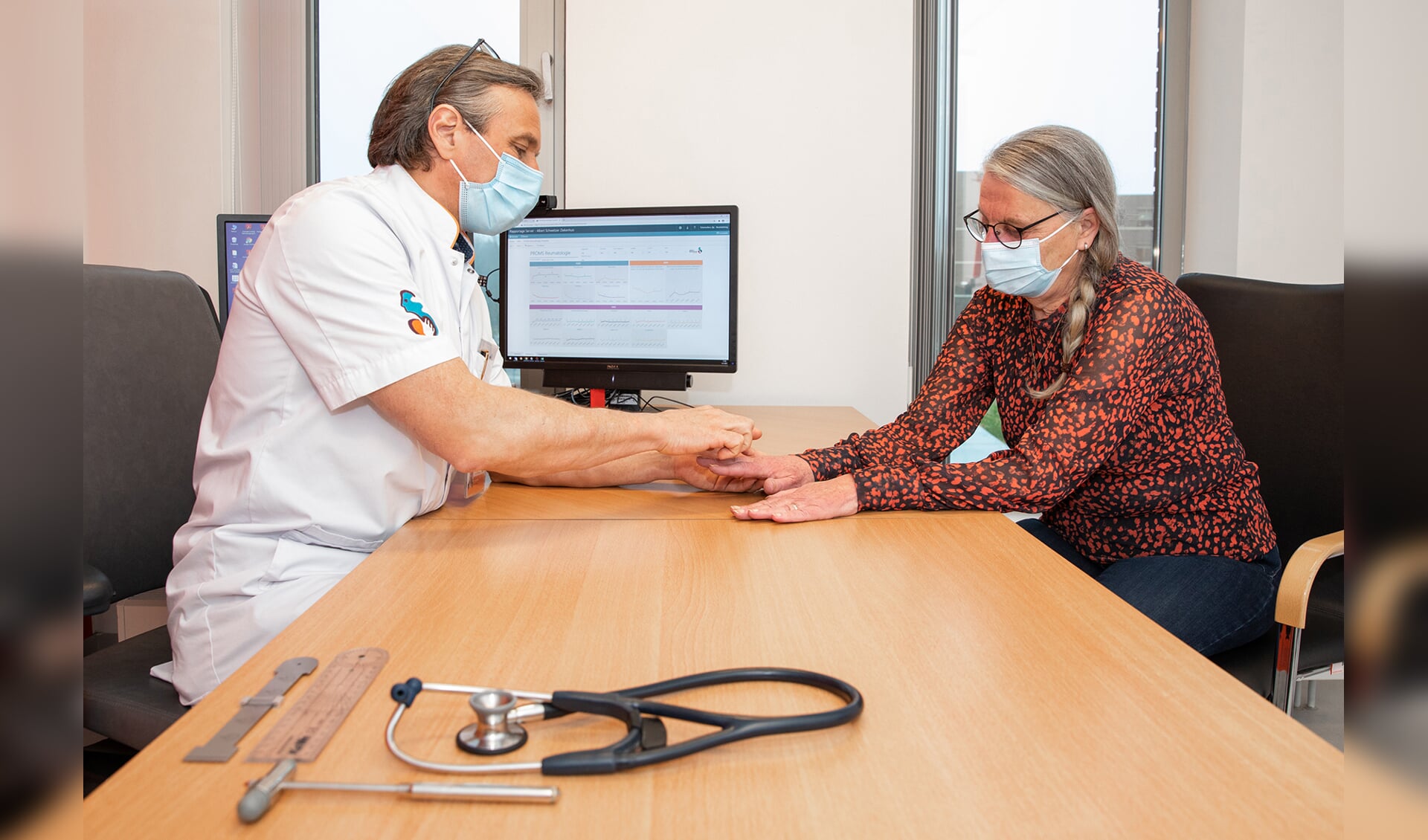 Reumatoloog Ilja Tchetverikov bekijkt met Klarie Stigter, de achthonderdste onderzoeksdeelneemster, de gevolgen van artritis psoriatica in haar handen.
