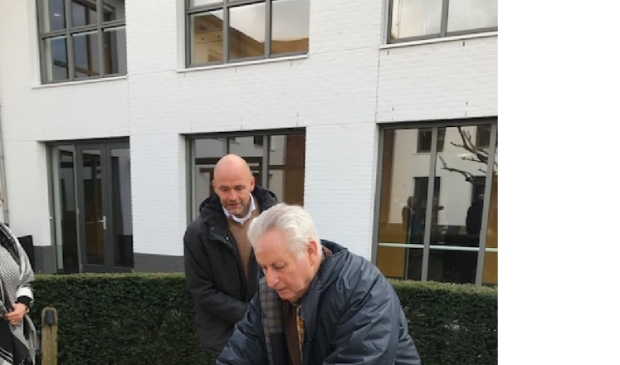 Felix Buijs bevestigt het plaatje van Meerwinkel op het bankje onder toeziend oog van Olivier Bongers