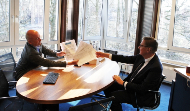 Een lid van het actiecomité overhandigt de honderden handtekeningen aan de wethouder.
