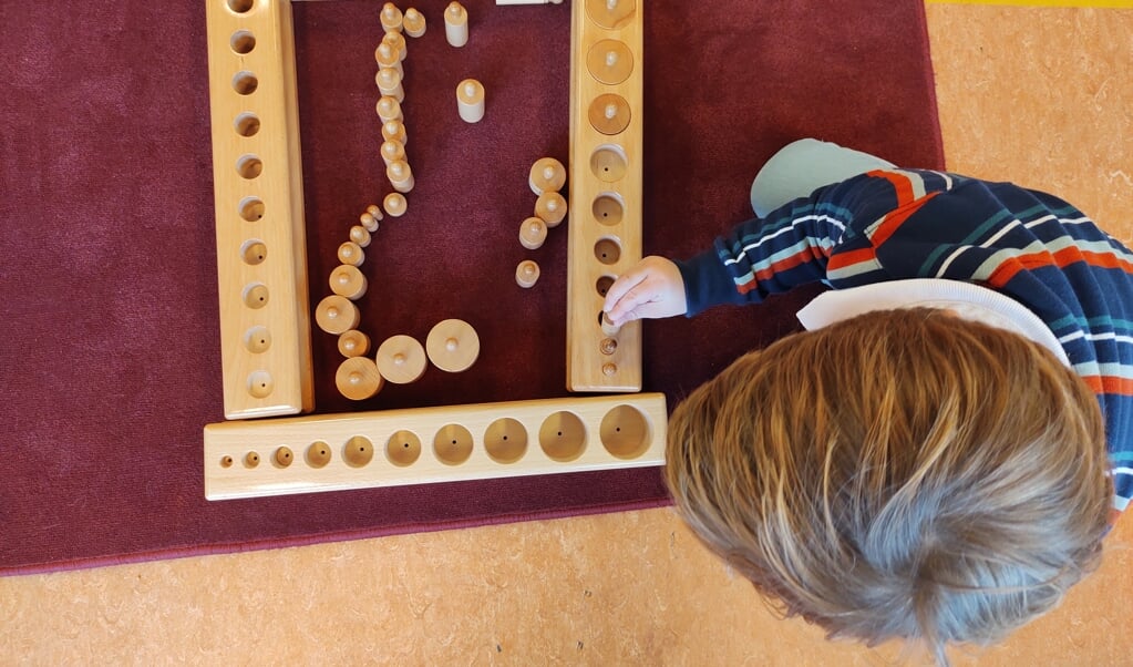 Leerling oefent met cilinderblokken (Montessorimateriaal)