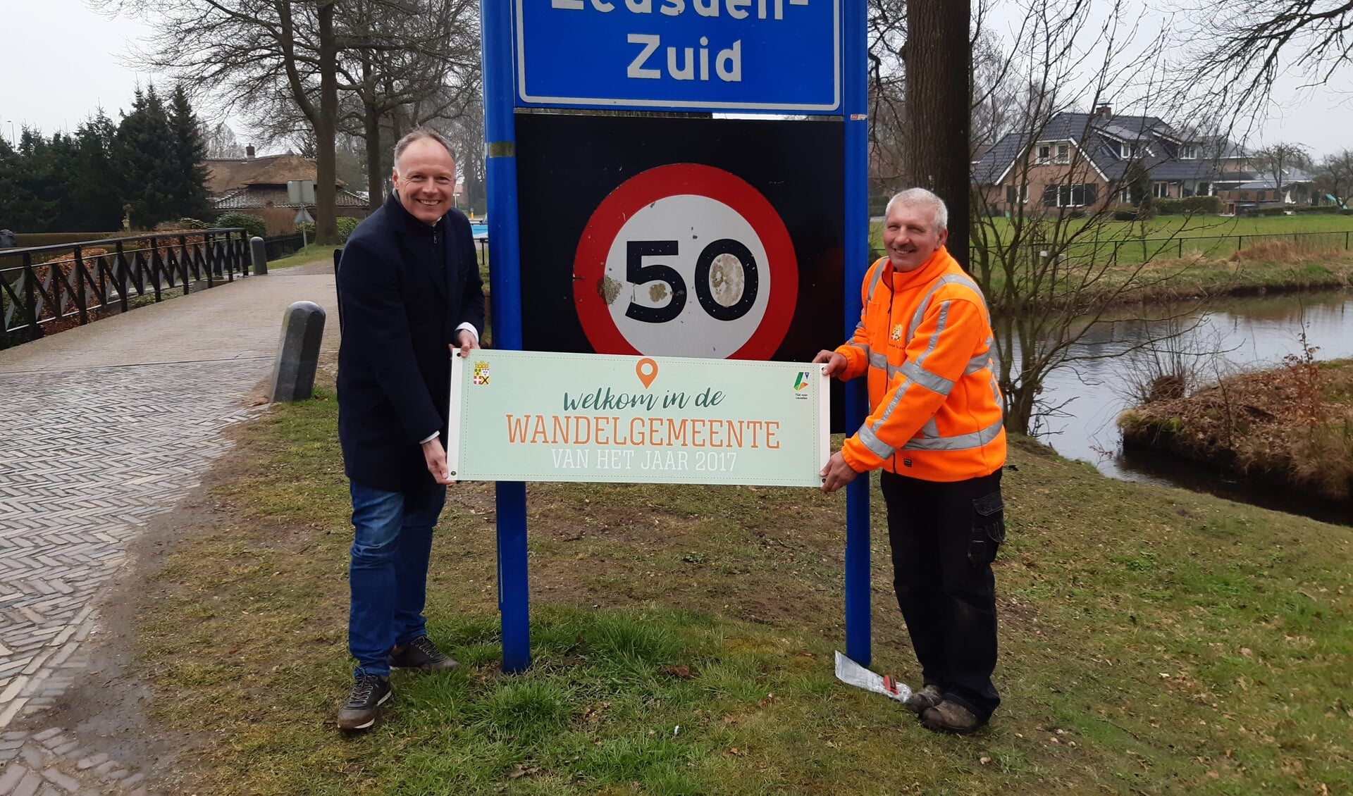 Wethouder Kiel en Henny Blijderveen van de gemeente Leusden staan op het punt het eerste bord terug te hangen.