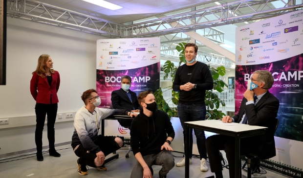 <p>Winnende studenten van ‘Team 18’, (links) Marlous Ten Kate, dagvoorzitter, (links achter bureau) Manish Dixit, opgavemanager Informatiesamenleving gemeente Veenendaal en (rechts achter bureau) Marco Verloop, wethouder gemeente Veenendaal.</p>