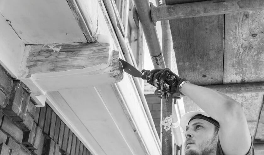 Timmerman in opleiding restaureert de dakgoot tijdens de renovatie van 'de Meester van Haarlem', voormalige Ambachtsschool en MTS aan de Verspronckweg.