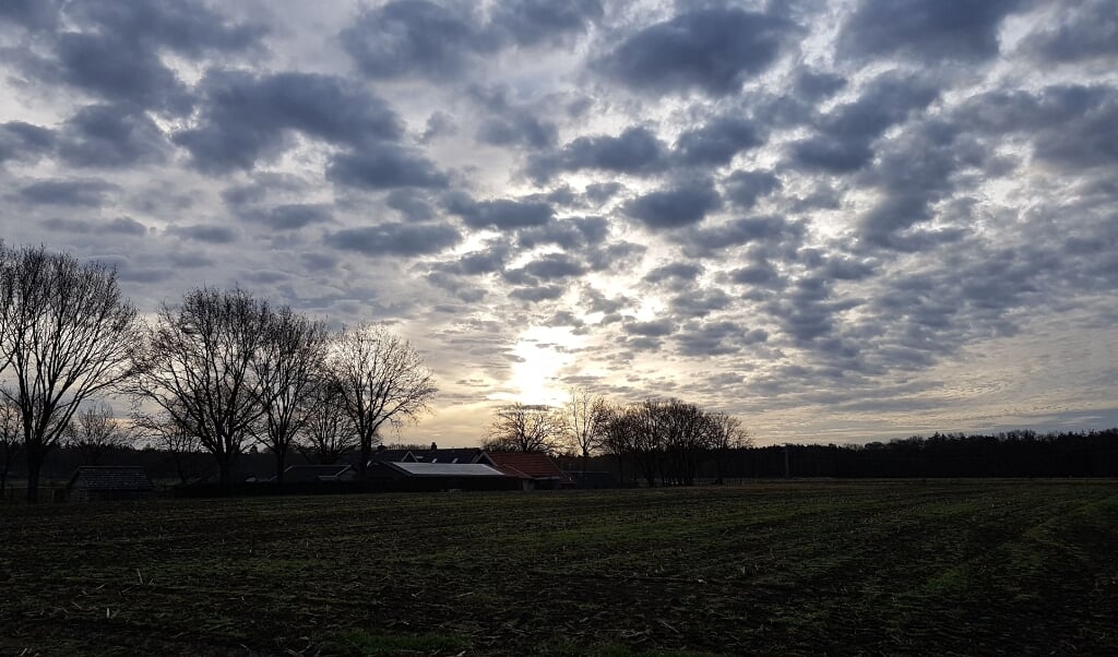 De zon breekt door over de kale vlakte.