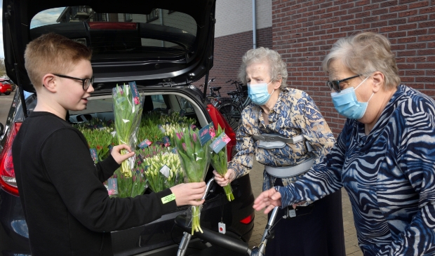 <p>Milan du Bois overhandigt tulpen aan bewoners van woonzorgcomplex De Samaritaan.</p>