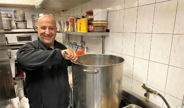<p>Safi Ibrahim bij zijn kookpan van honderd liter.</p>