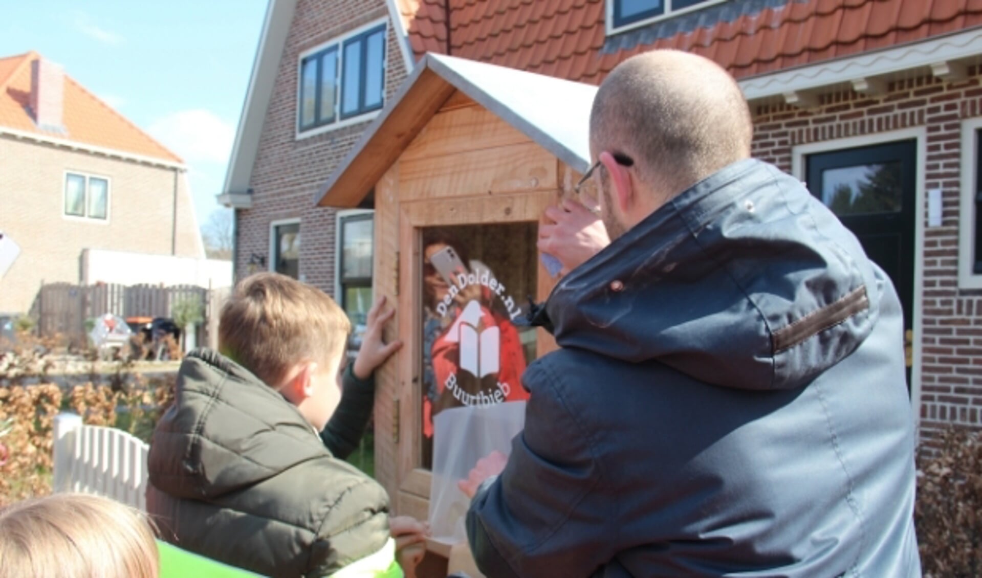 Paul van DenDolder.nl en Koen en Tim plakken de Buurtbieb-sticker op het deurtje.