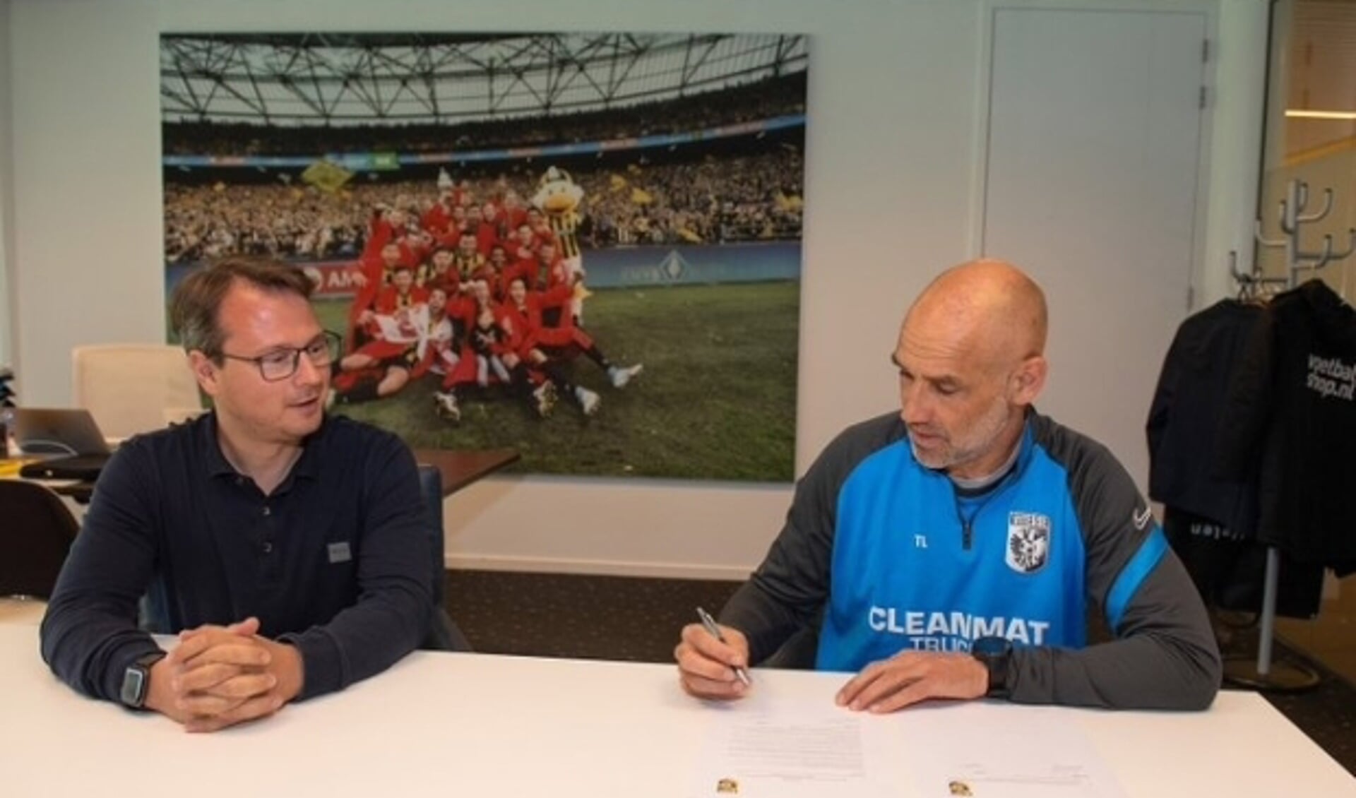 Onder toeziend oog van technisch directeur van Vitesse, Johannes Spors, ondertekent hoofdtrainer Thomas Letsch zijn nieuwe, opengebroken, contract.