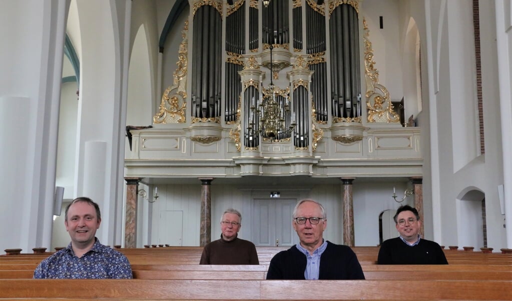 Vier leden van de renovatiecommissie in de kerkzaal voor het orgel: Leander van der Steen, Berend van Steenbeek, Bert van de Hoeve en Addy Hekking.