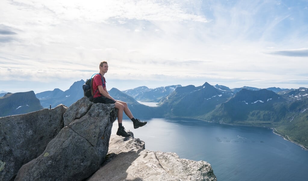 Sven geniet van het uitzicht bovenop de Segla berg in Noorwegen.