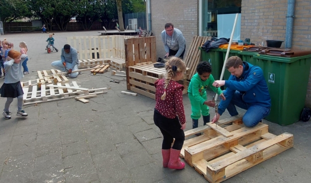 Kleuters van de Koepelschool maken onder leiding van vier handige vaders een modderkeuken en een loungebank