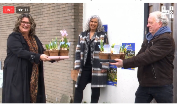 <p>Bewoner van in Overbos Jan Havenaar krijgt van wethouder Steffens enkele plantjes voor zijn geveltuin. NMCX-directeur Arjanne Lagendijk kijkt toe. </p>