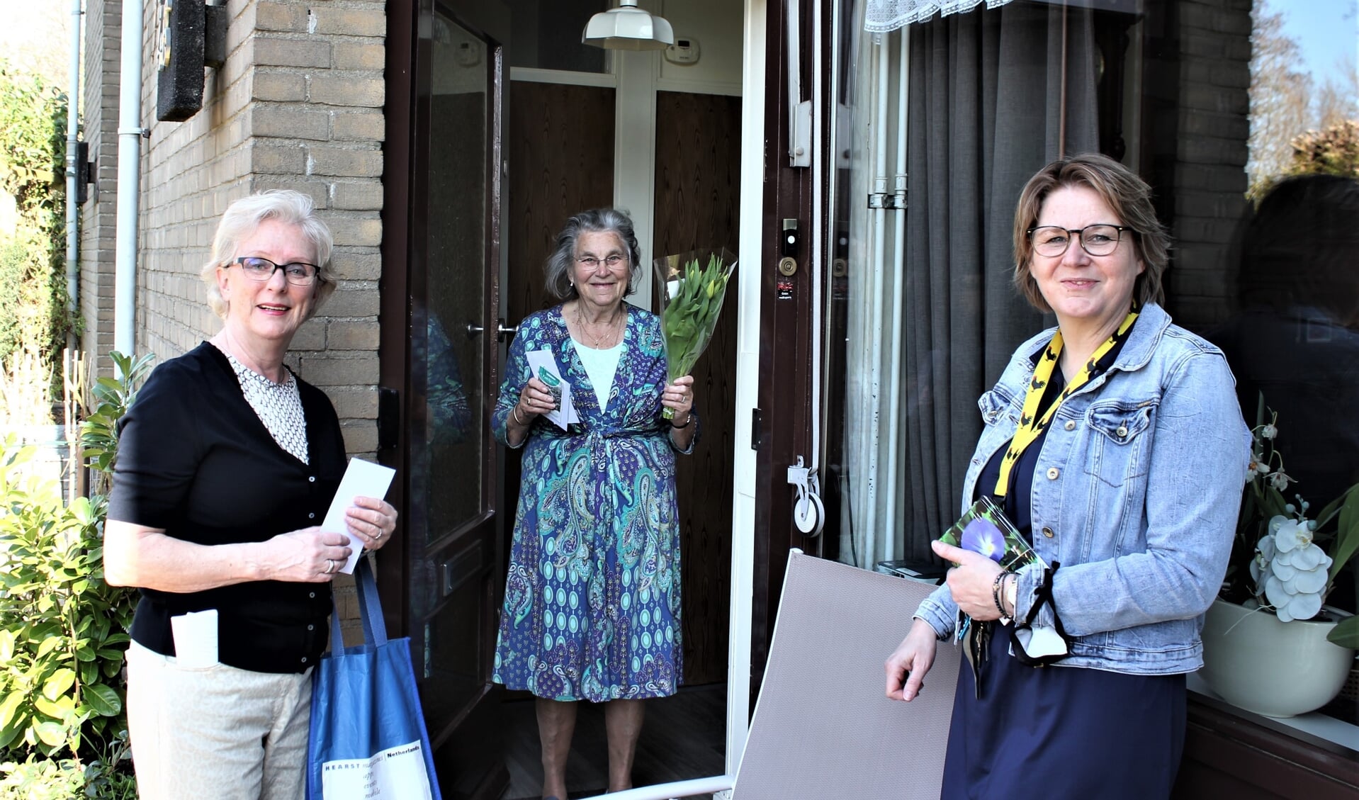 Jeanine Schaling van de Coalitie Erbij Woudenberg brengt samen met wethouder bloemen naar bezoekers van Samen op Zondagbren