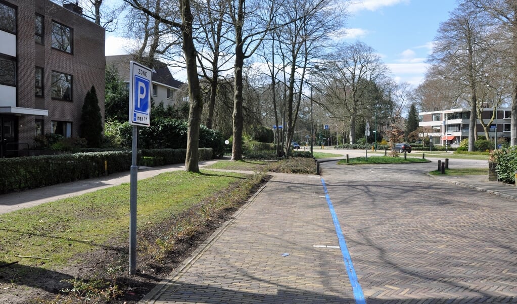 De blauwe zone voor drie parkeerplaatsen aan de Kettingweg. Rechts in de verte appartementencomplex Baarnsteijn.