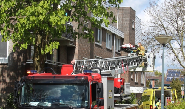 Brandweer hijst vrouw haar woning binnen.