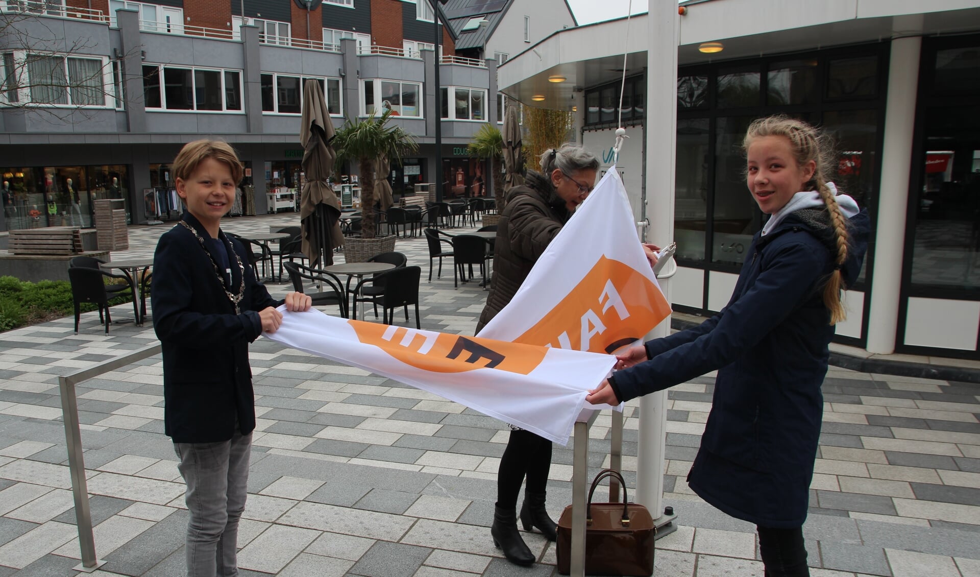 Pim van Gellecum en Eloïse van der Ham assisteren bij het hijsen van de Fairtrade Gemeente-vlag.