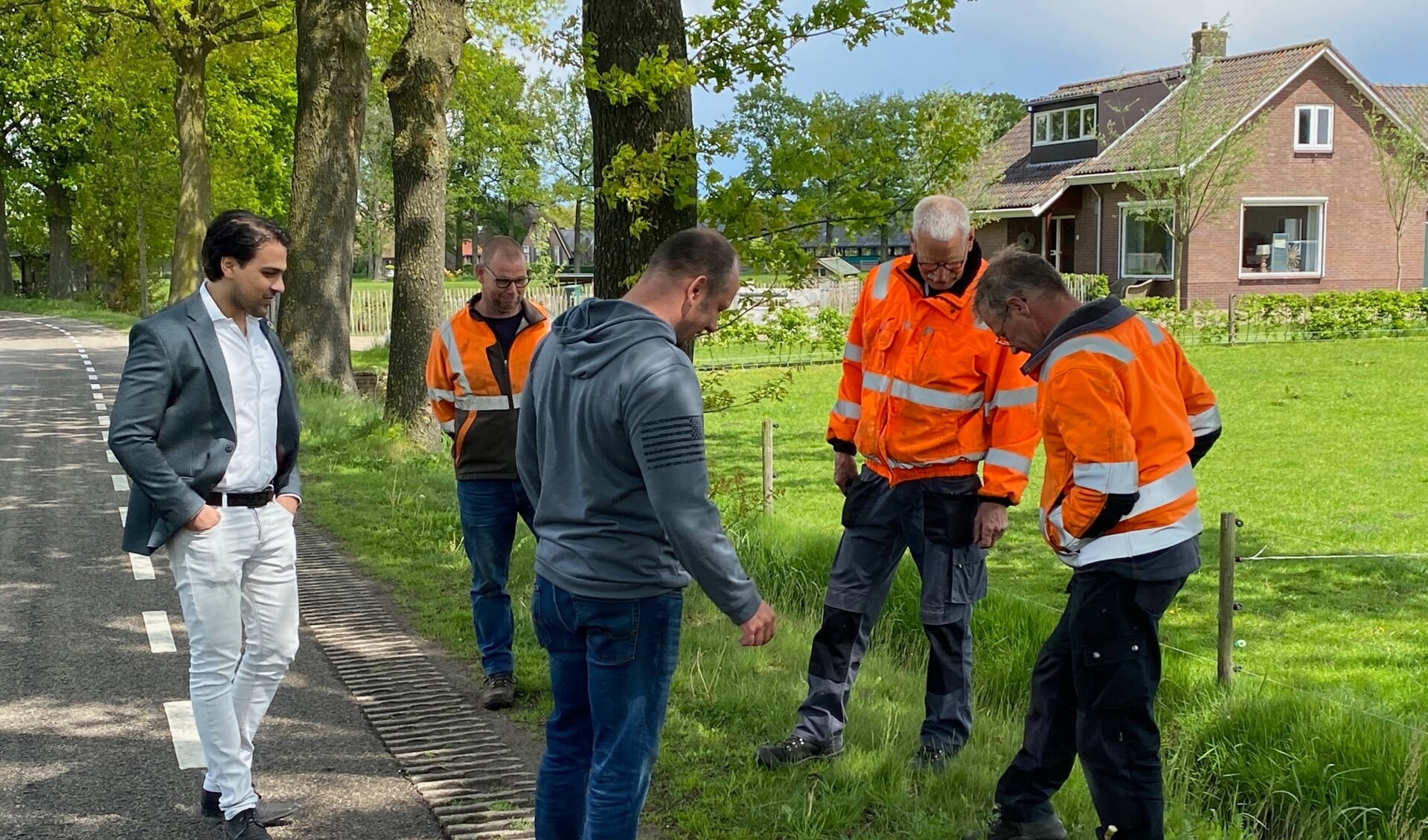 Wethouder Sander van 't Foort inspecteert met medewerkers van Omgevingsbeheer planten in de wegberm.