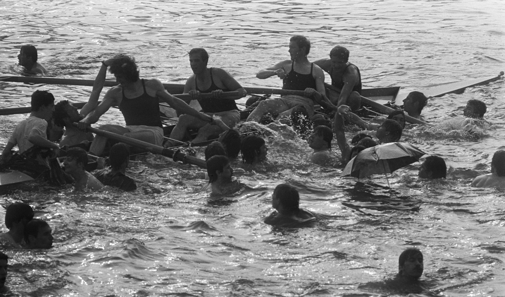 Roeiers omringd door zwemmende supporters op 7 mei 1972