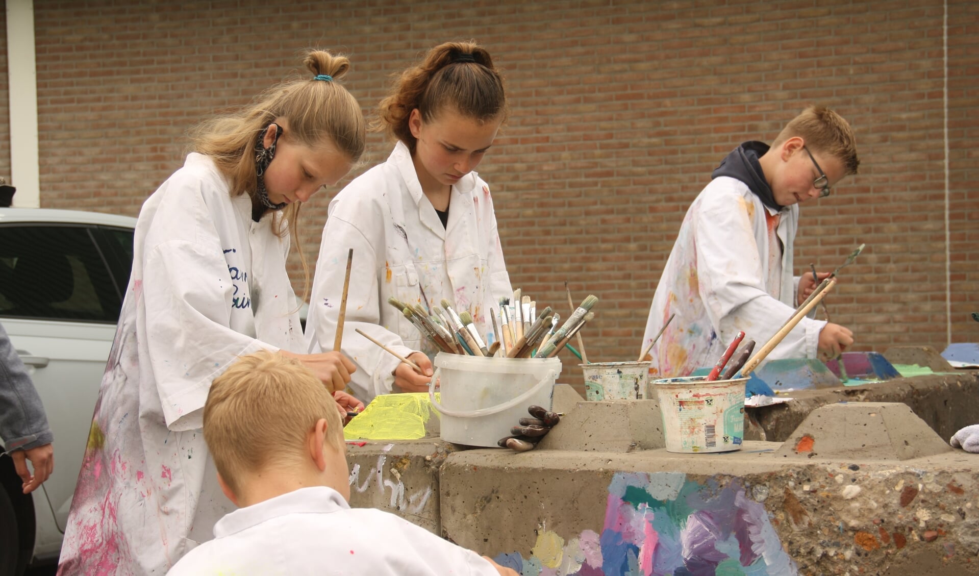 Leerlingen van 't Startblok en de Jozefschool in Achterveld staken dinsdagochtend de handen uit de mouwen om de betonnen muurtjes op te vrolijken. 