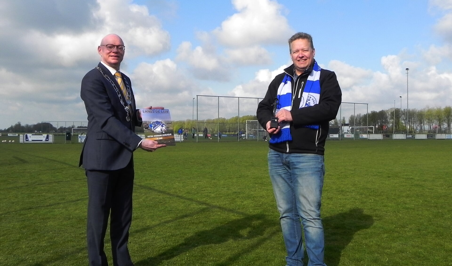 Burgemeester Gilbert Isabella ontvangt uit handen van voorzitter Ton Vernooij het jubileumboek "Langs de Lijn".