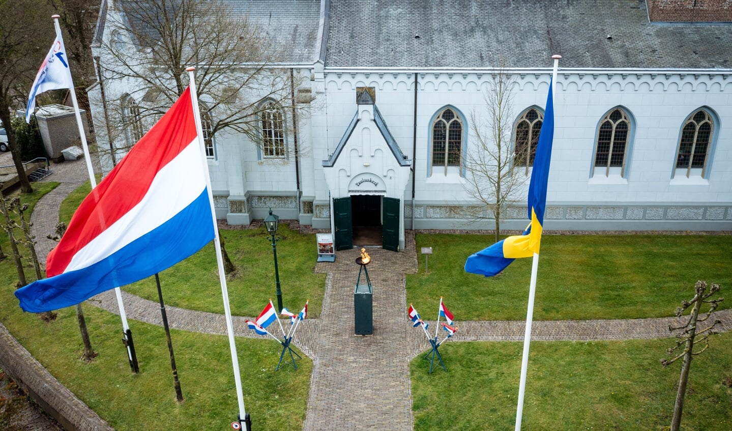 Het bevrijdingsvuur temidden van de nationale driekleur en de vlag van Baarn voor de Pauluskerk. 