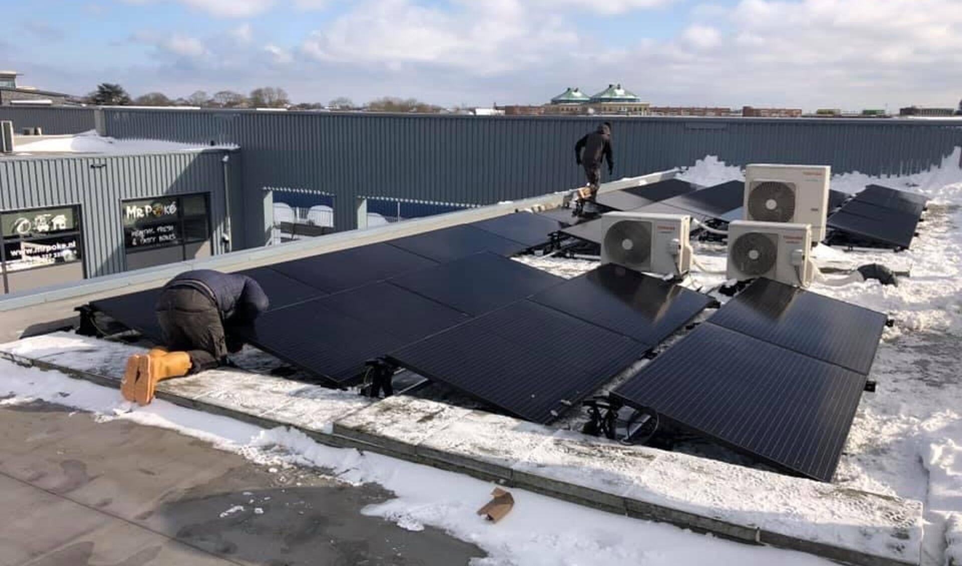Installatie van zonnepanelen op het dak van een bedrijfspand.