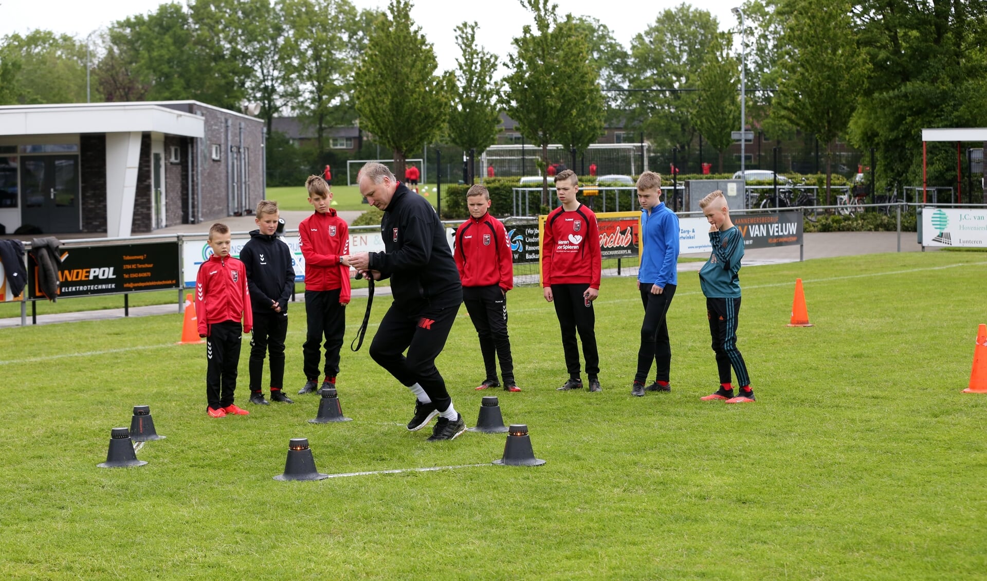 Wim snijders doet een oefening met Smartgoals voor. De jeugdspelers van Terschuurse Boys zijn aandachtige toeschouwers.