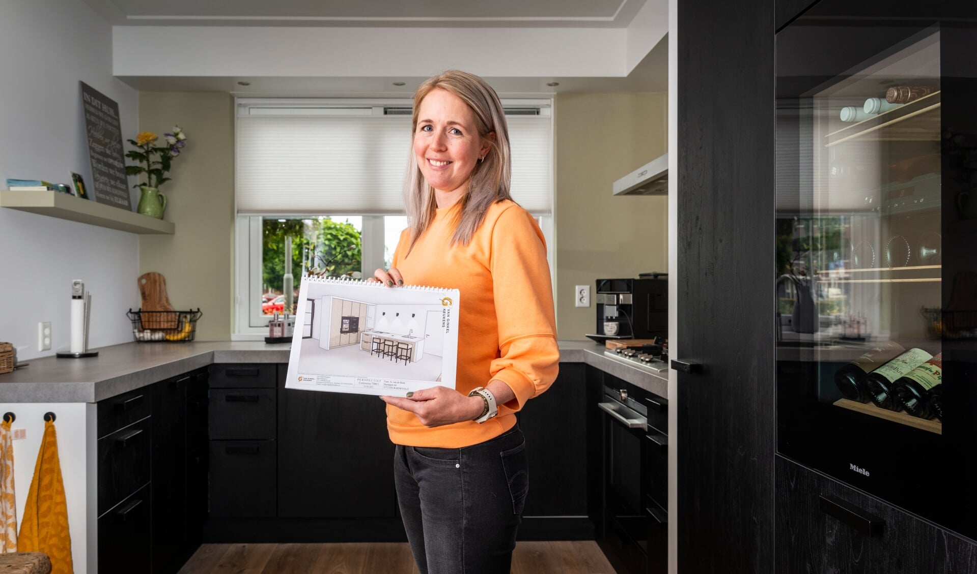 Gonda van de Beek in haar huidige keuken van Van Ginkel Keukens. In haar hand het ontwerp van de nieuwe keuken.
