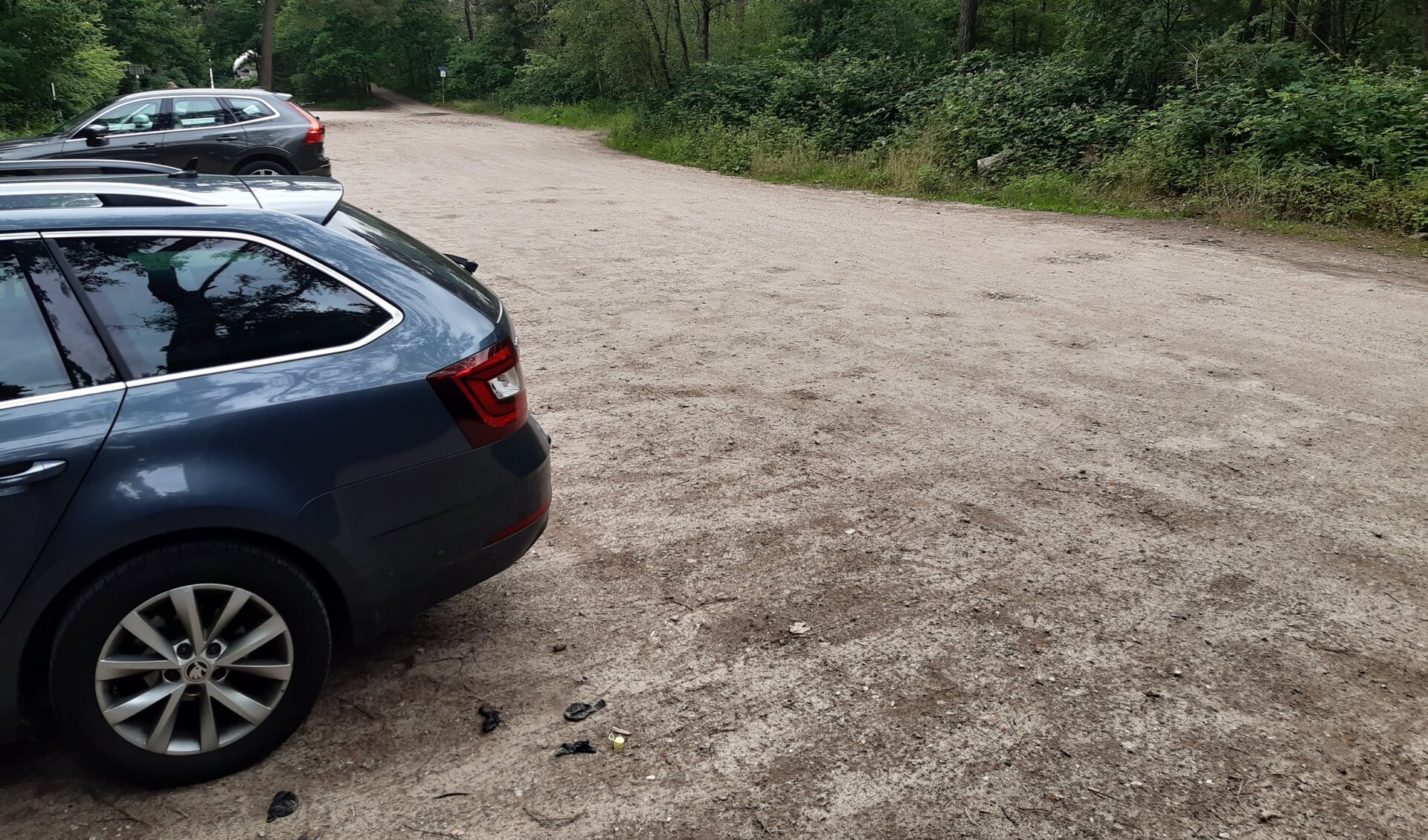 De nu nog onverharde, 'illegale' parkeerplaats aan de Dodeweg waarover het landgoed Den Treek-Henschoten in de clinch ligt met de gemeente.De oprit naar de bestaande fietsbrug is nog net zichtbaar.