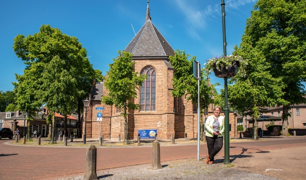 <p>Wethouder Henny van Dijk bij een van de onlangs opgehangen bloembakken in het dorpscentrum.</p>