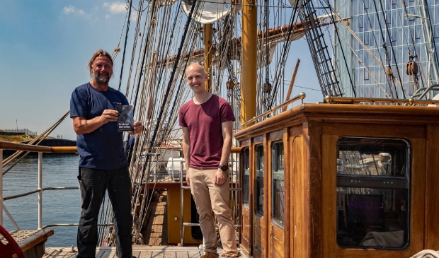 Kapitein Eric Kesteloo en schrijver Boris Lemereis op Bark Europa bij de overhandiging van het boek