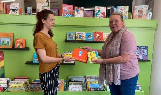 <p>Liesbeth Versteeg van de Bibliotheek Z-O-U-T reikt een BoekStartkoffertje uit en laat de baby- en dreumesboekjes zien.</p>