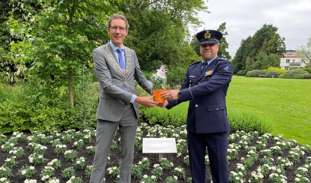 <p>Burgemeester Tjapko Poppens overhandigt veteraan Martijn Neumeier een pot met witte anjers..</p>