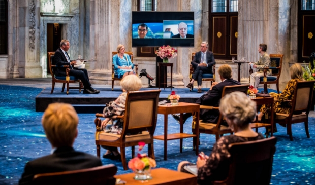 Gastsprekers vertellen over de historische en psychologische dimensies van de huidige coronapandemie. Op de voorgrond de koninklijke familie. Mely van Malenstein midden in het panel.