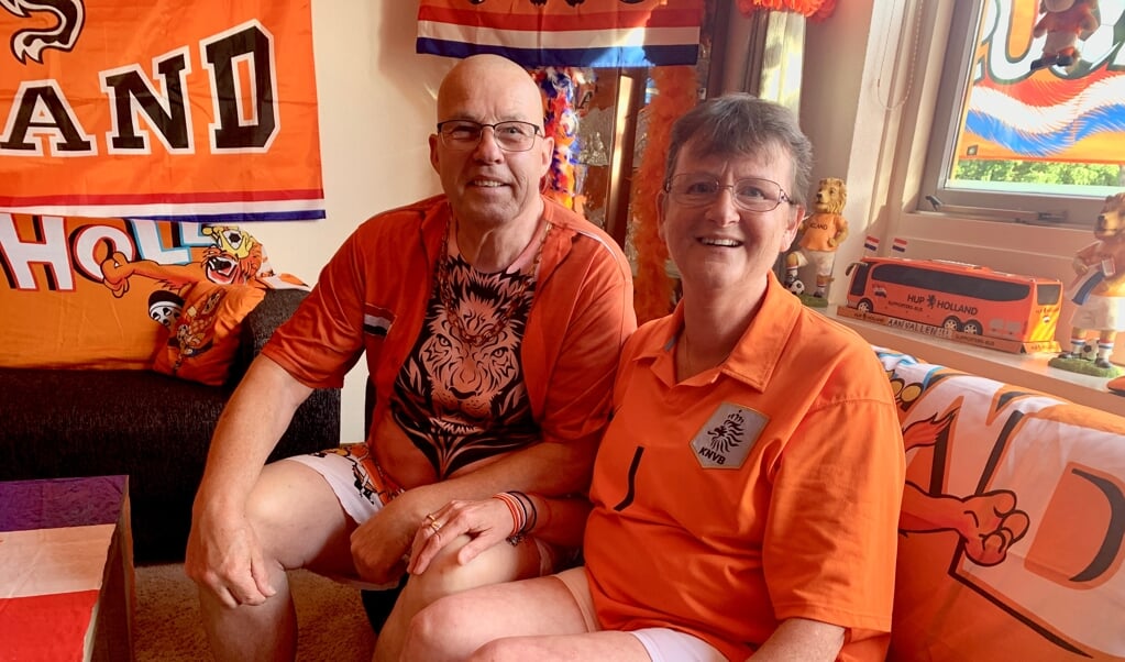 Marten en Hennie op de bank in hun huis vol oranjeversiering. 