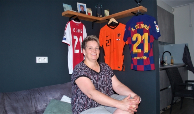 <p>Marjon Schuchhard met enkele prominente shirts van haar zoon Frenkie, in zijn ouderlijk huis in Arkel.</p>