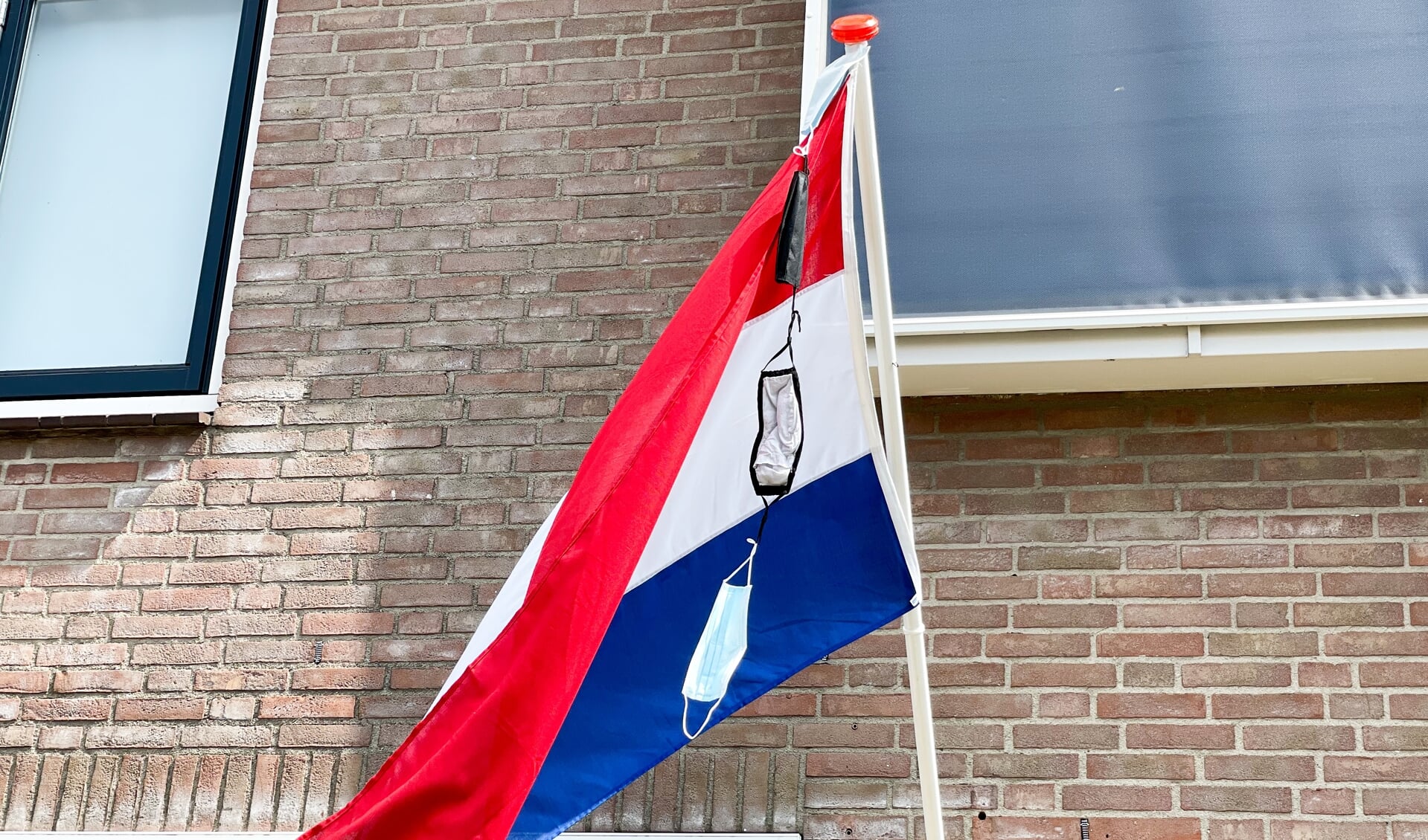 De vlag met mondkapjeswimpel wapperde sierlijk aan het huis in Nijkerkerveen