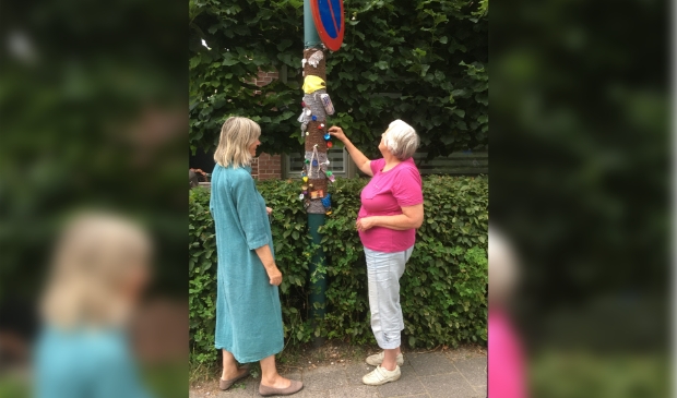 De maakster van het werk laat het aan een buurvrouw zien