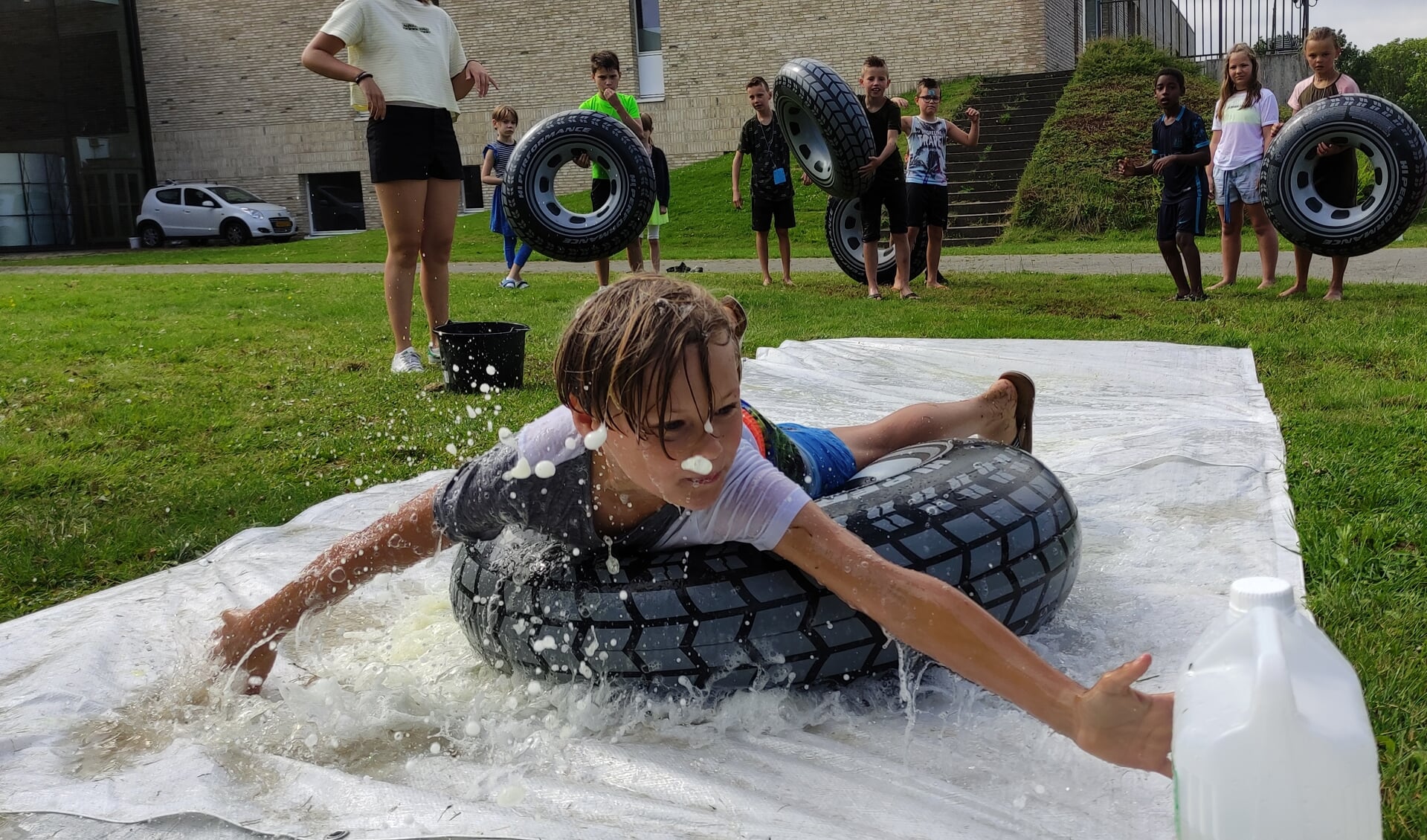 Terwijl het water om zijn oren spettert, glijdt een jonge deelnemer aan de VakantieBijbelWeek over het plastic.