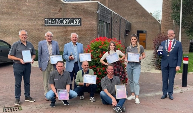 Staand v.l.n.r. voorzitter Henk in ’t Veld, jubilarissen Jo Zandee, Bert Ippel, Femke Zandee, Gerja Kooijman en burgemeester Servaas Stoop Voorste rij v.l.n.r. Bertho van Mourik, Johan Zandee en Johan Ouwerkerk