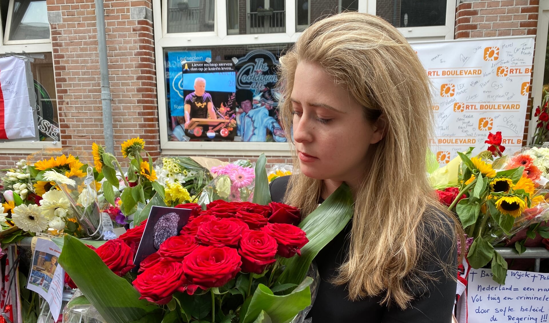 Nathalie de Bruin met een bos rode rozen op de plek waar Peter R. de Vries in Amsterdam werd neergeschoten.