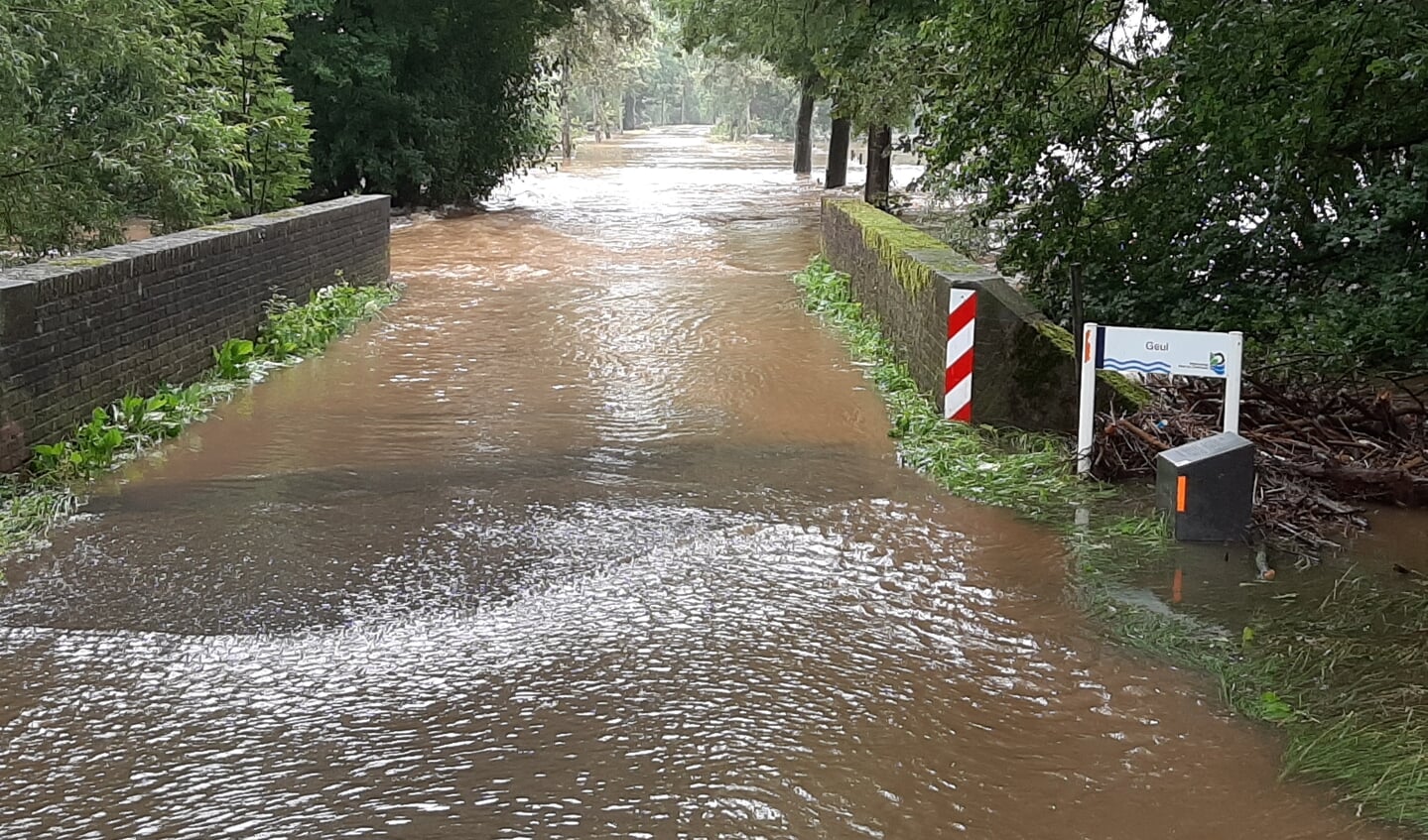 'De overstroomde weg naar dorp Partij onder aan de Gulperberg, in Zuid-Limburg op donderdag 15 juli. Onder een waterig zonnetje veranderde het riviertje de Geul, normaal een stroompje van maximaal 5 meter breed, deze zomer in een soort Amazone.'