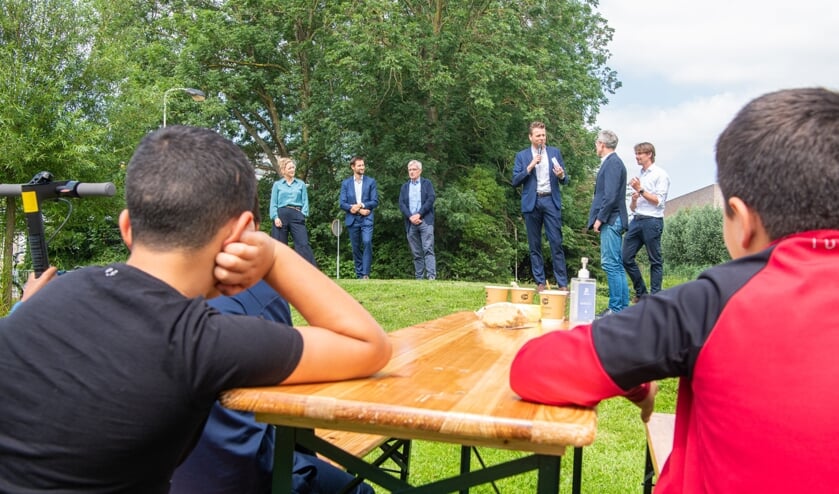 Onder het toeziend oog van enkele jonge bewoners van de wijk leggen de bestuurders de plannen uit aan de aanwezigen