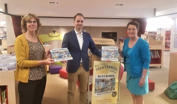 Liesbeth van Brink (l) en Irini Boxma (r) nemen dankbaar de boeken in ontvangst van Juriën Koster.