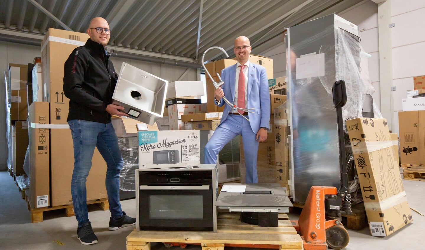 Eigenaar Johan van Velthuizen en keukendesigner Wilbrand Hardeman poseren tussen de onderdelen en apparaten.