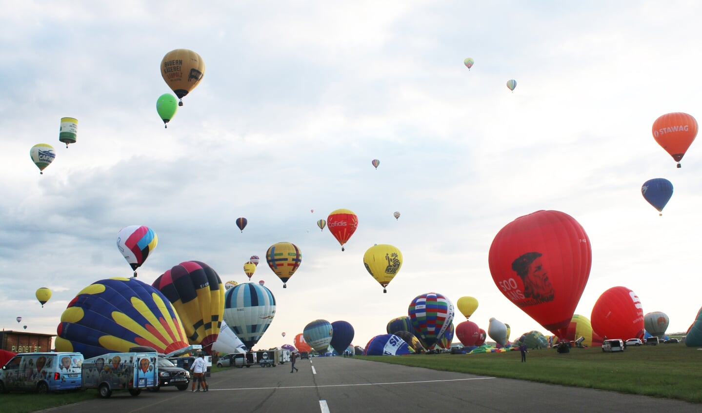 Links en rechts van de landingsbaan worden de ballons opgeblazen om daarna te vertrekken. Je komt ogen te kort.