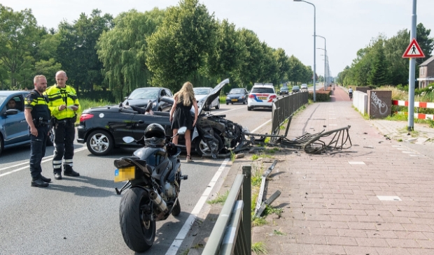 <p>De vrouw bekijkt de schade van de auto.</p>